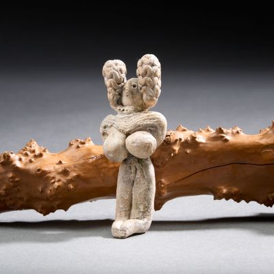 une figurine représentant une personne assise sur une branche d'arbre