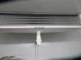 a white air conditioner sitting on a shelf next to a wall