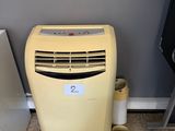 un petit climatiseur posé à côté d'un réfrigérateur