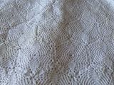 a white crocheted blanket on a bed