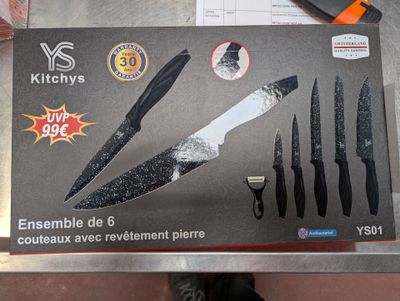 une boîte de couteaux et une paire de ciseaux posés sur une table