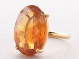 a close up of a ring with an orange stone in it