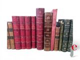 several old books are lined up in a row on a white surface