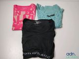 three t - shirts sitting on top of a white table next to each other