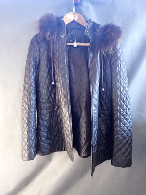 black leather jacket with fur collar and cuffs hanging on a hanger