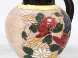 un vase avec des fleurs peintes dessus, posé sur une table