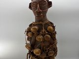 an old wooden figurine of a man with a hat and a bunch of nuts on his head