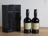 deux bouteilles de vin posées à côté d'une boîte noire sur une table