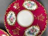 a red plate with a gold rim and a pink plate with flowers on it