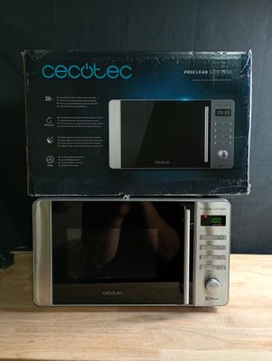 une boîte posée sur un micro-ondes, lui-même posé sur une table en bois