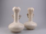 two white vases sitting next to each other on a table