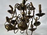 un lustre ancien en laiton à cinq branches, surmonté d'une clochette suspendue au plafond