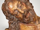 statue of a man with a beard and a bearded face resting on a piece of wood