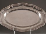 un plat en argent ancien posé sur un socle, sur fond noir