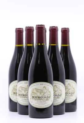quatre bouteilles de vin rouge sont alignées sur une surface blanche