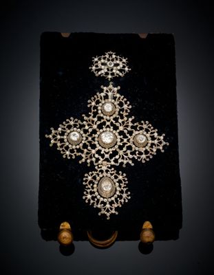 un gros plan d'une croix ornée de perles posée sur une surface noire