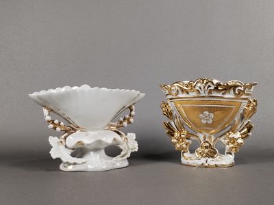 deux vases blancs et dorés posés l'un à côté de l'autre sur une table