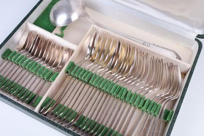 des couverts dans une boîte munie de poignées vertes et contenant des cuillères