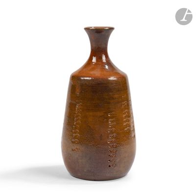 un vase brun posé sur une surface blanche
