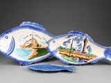 two fish shaped dishes on display on a table