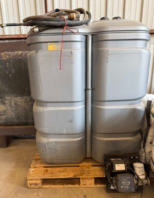 deux fûts gris posés sur une palette dans un entrepôt