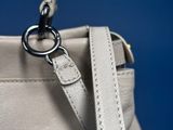 a white purse with a metal handle on a blue background