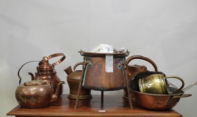 de nombreuses casseroles et poêles en cuivre posées sur une table en bois