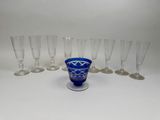 six blue glass goblets and six empty wine glasses on a white surface