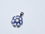 une image représentant un pendentif en forme de fleur bleue et blanche posé sur une surface blanche