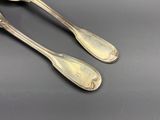 une paire de cuillères anciennes en argent et un repose-cuillère posés sur un support noir