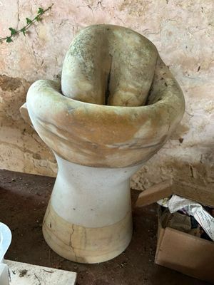 a statue of a person sitting on top of a toilet