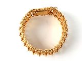 a close up of a gold bracelet on a white surface