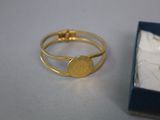 a gold ring with a coin on it next to a box