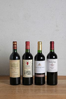 quatre bouteilles de vin sont alignées sur une table en bois