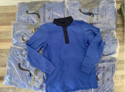 a blue shirt with a black collar laying on the floor