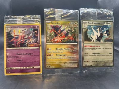 trois cartes Pokémon dans des pochettes en plastique posées sur une table
