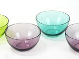 three different colored glass bowls sitting on a white surface