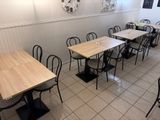 tables and chairs are lined up in a restaurant with a clock on the wall