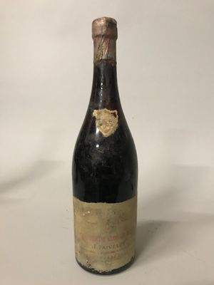 une vieille bouteille de vin posée sur une table blanche