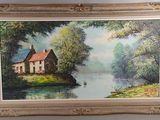 tableau représentant une maison au bord d'une rivière, encadré et accroché au mur