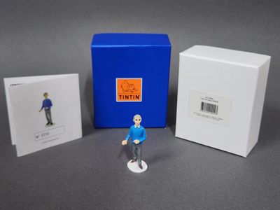 une petite figurine représentant un homme debout à côté d'une cabine téléphonique bleue