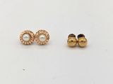 une paire de boucles d'oreilles en or et perles posées sur un fond blanc