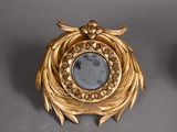 a gold clock with a mirror in the middle of it