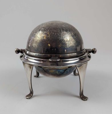 un vieux plateau en argent orné d'un globe terrestre, posé sur un socle