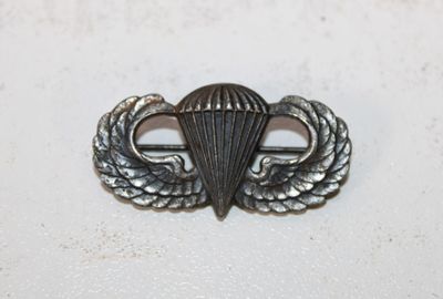a close up of a metal pin with a parachute on it