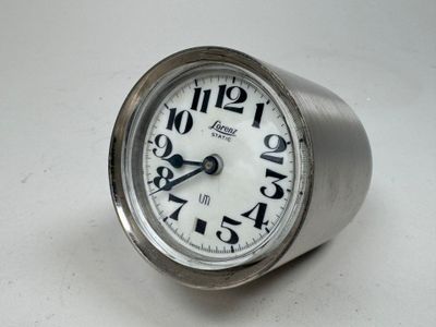 une horloge argentée avec des chiffres, posée sur un fond blanc