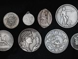 six médailles d'argent de différentes tailles et formes sur fond noir