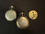three silver and gold pocket watches on a black surface