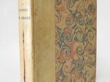 an old book sitting on top of a white table next to a white wall