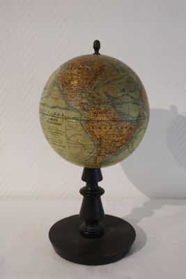 un petit globe posé sur un socle noir, lui-même posé sur une surface blanche